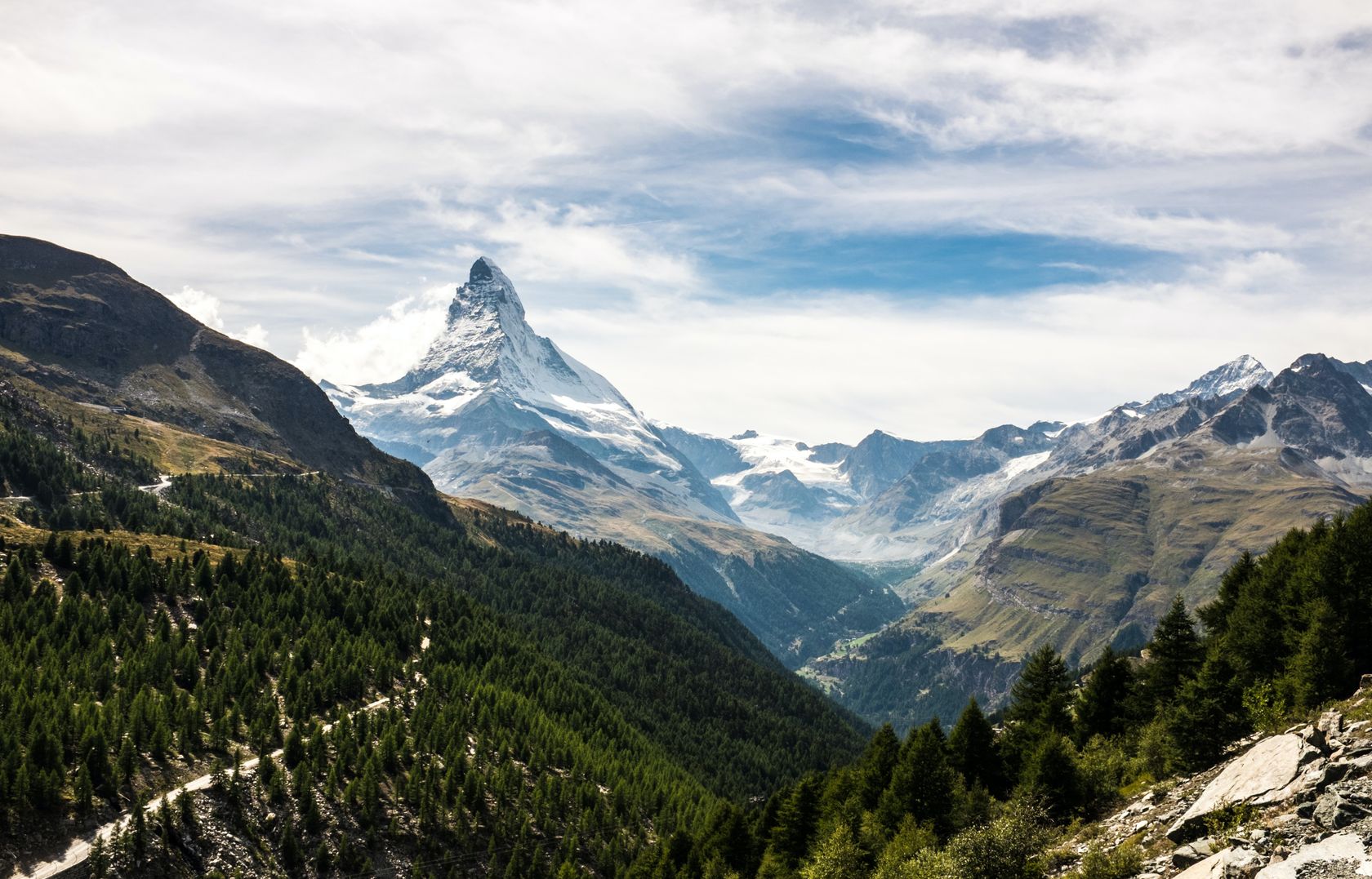 The Matterhorn in the distance, framed though a forested valley against a blue sky